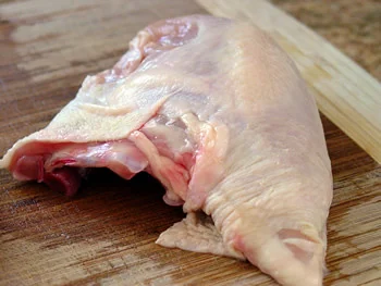 Raw skin-on chicken breast with the bone attached
