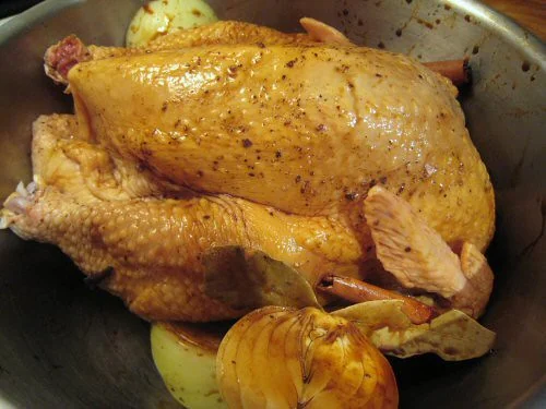 A raw whole chicken coated in marinade before rotisserie cooking